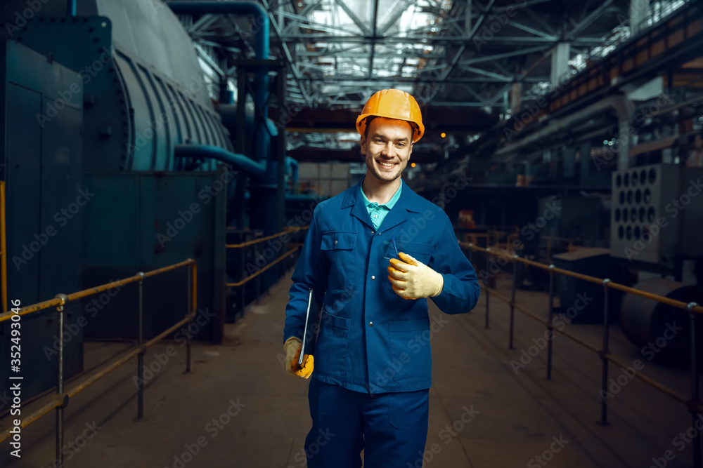 Smiling worker holds notebook, factory floor Smiling worker holds notebook, factory floor
