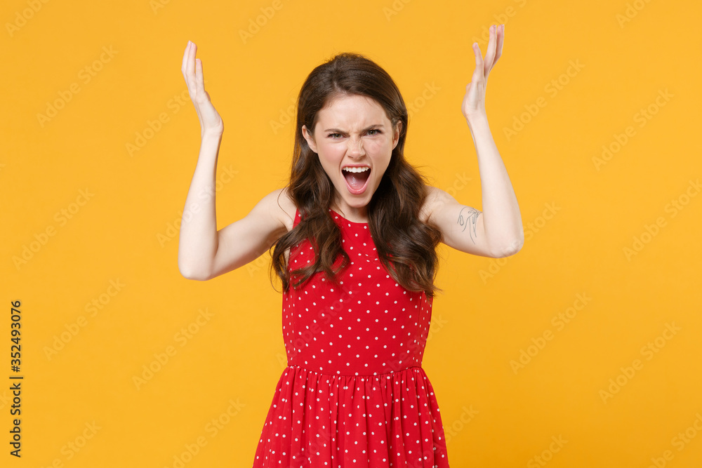 Angry irritated young brunette woman girl in red summer dress posing isolated on yellow background studio portrait. People lifestyle concept. Mock up copy space. Spreading hands, screaming swearing. Angry irritated young brunette woman girl in red summer dress posing isolated on yellow background studio portrait. People lifestyle concept. Mock up copy space. Spreading hands, screaming swearing.