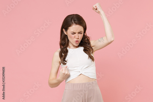 Happy young brunette woman girl in light casual clothes posing isolated on pastel pink wall background studio portrait. People emotions lifestyle concept. Mock up copy space. Doing winner gesture.