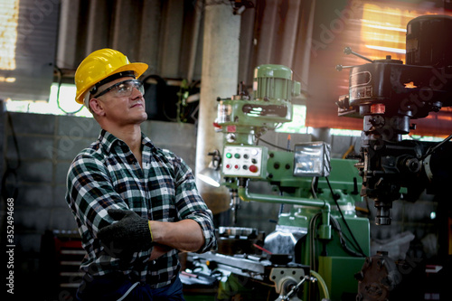 Industrial engineer worker wearing helmet and safe glasses operating with machinery at manufacturing plant factory, working with machine in industry concept