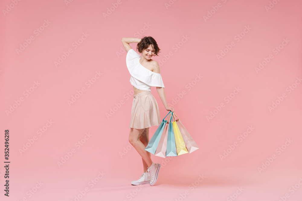 Side view of smiling young woman girl in summer clothes hold package bag with purchases isolated on pastel pink wall background. Shopping discount sale concept. Mock up copy space. Put hand on head. Side view of smiling young woman girl in summer clothes hold package bag with purchases isolated on pastel pink wall background. Shopping discount sale concept. Mock up copy space. Put hand on head.