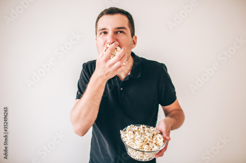 Young man isolated over white background. Guy eating popcorn from bowl. Tasty delisious snack. Glutton man divour meal. photo