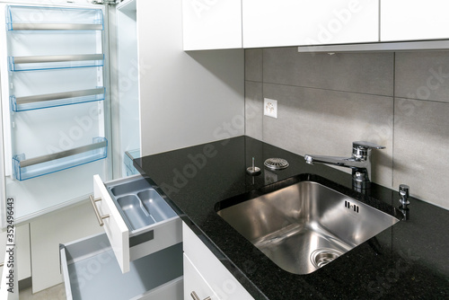 interior view of simple and modern kitchen in gray and white with black stone work top