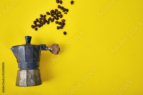 Flat lay of Coffee maker and coffee beans on yellow background.
