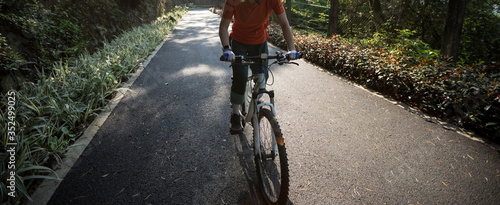 Woman cycling on bike path at park on sunny day