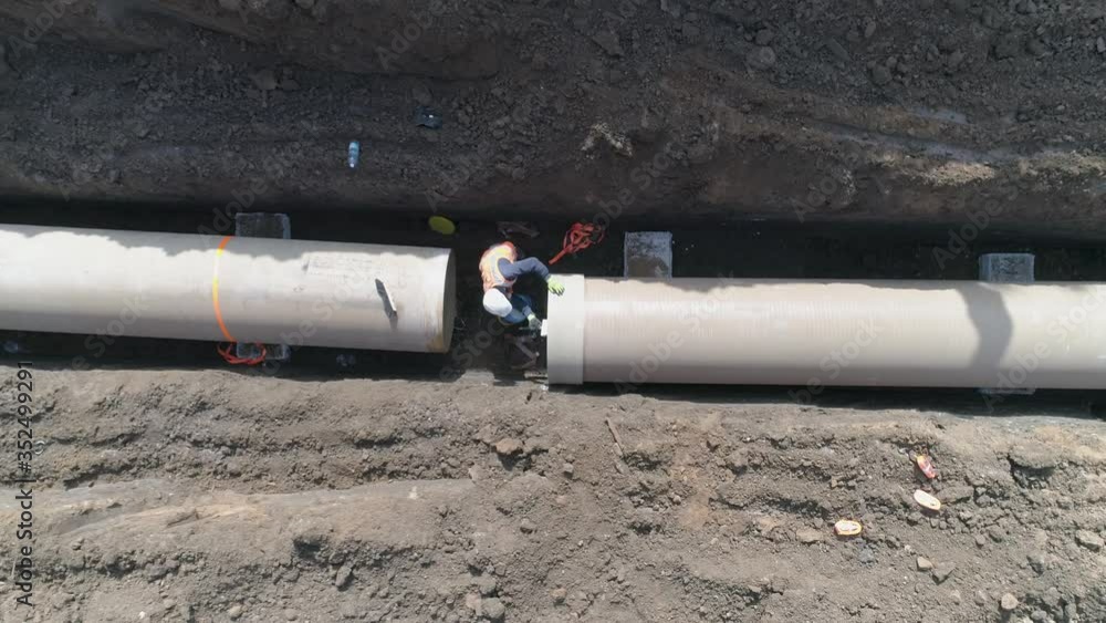 Concrete pipe tube installation. Aerial above men at work outside with