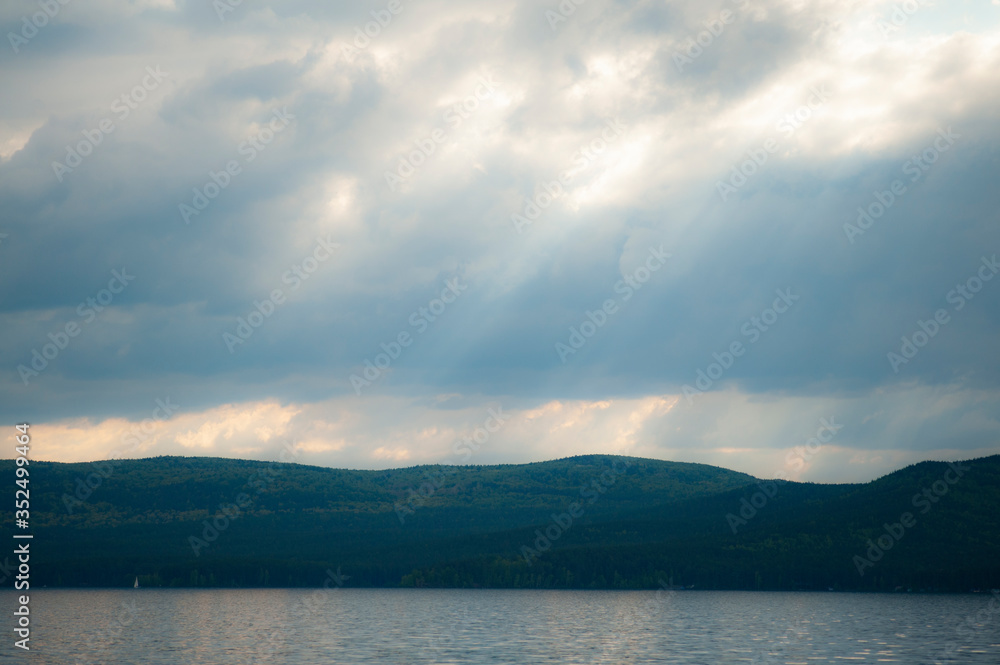 beautiful cloudy sky with sunbeams in the background mountains