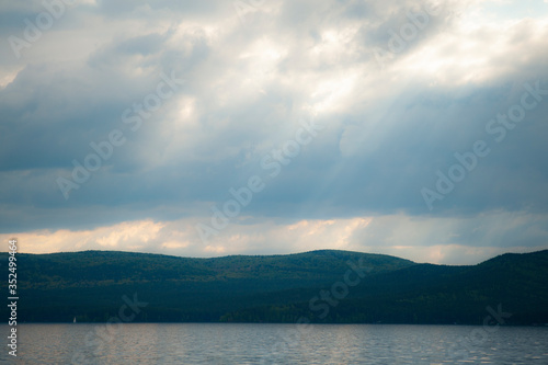 beautiful cloudy sky with sunbeams in the background mountains