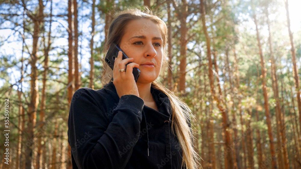 Portrait of beautiful young woman using smartphone in pine forest Portrait of beautiful young woman using smartphone in pine forest