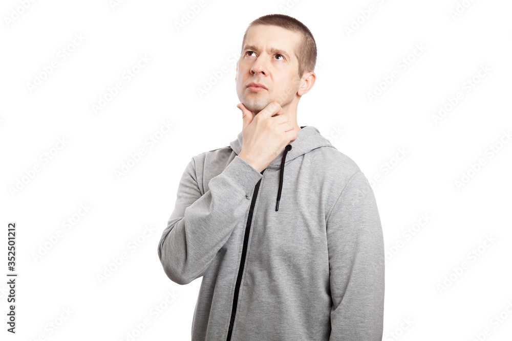 brooding, insecure male athlete makes a decision, a hand at the chin. Dressed in a grey hooded jacket. Look in upwards. Isolated brooding, insecure male athlete makes a decision, a hand at the chin. Dressed in a grey hooded jacket. Look in upwards. Isolated
