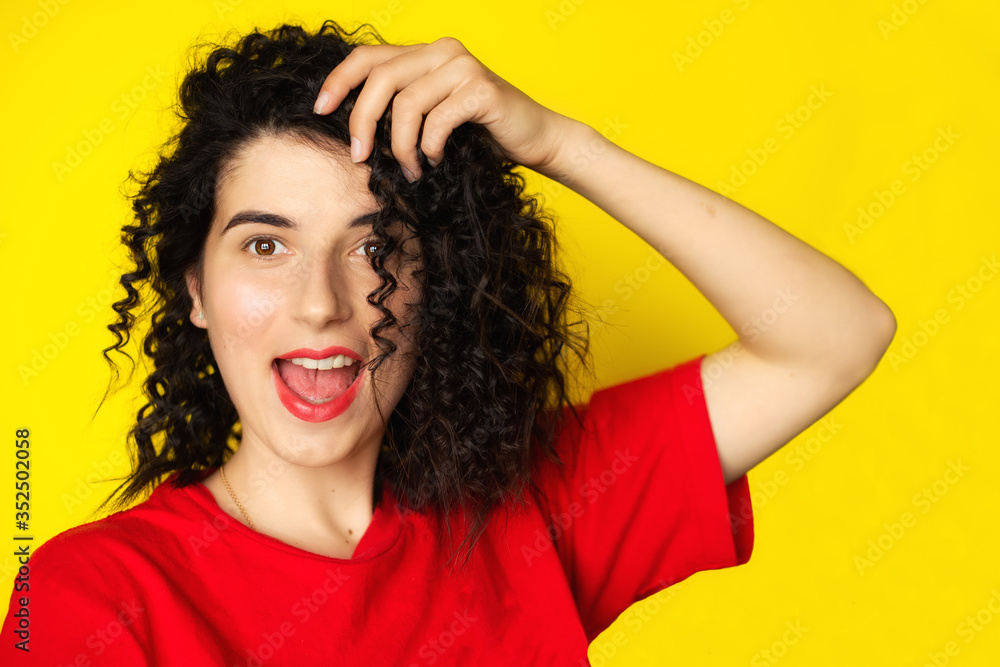 Charming young girl with curly black hair in a red T-shirt on a yellow background. Portrait photography. Emotions, facial expressions. Curls, Brunette. Red lipstick
Charming young girl with curly black hair in a red T-shirt on a yellow background. Portrait photography. Emotions, facial expressions. Curls, Brunette. Red lipstick