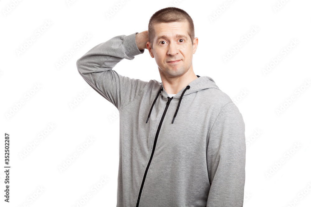 Obraz premium thoughtful, hesitant insecure male athlete makes a decision, hand by head. Dressed in a grey hooded jacket. looks in up. Isolated