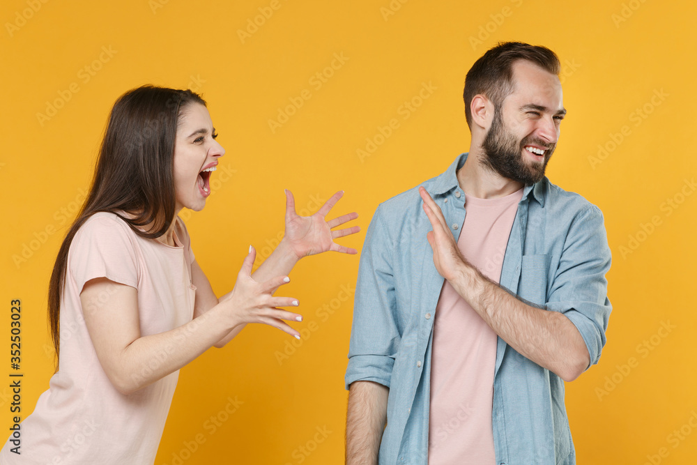Angry young couple friends guy girl in casual clothes isolated on yellow background. People lifestyle concept. Mock up copy space. Spreading hands, screaming swearing, showing stop gesture with palm. Angry young couple friends guy girl in casual clothes isolated on yellow background. People lifestyle concept. Mock up copy space. Spreading hands, screaming swearing, showing stop gesture with palm.