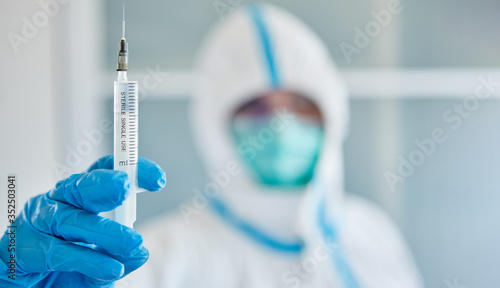 Forscher in Schutzkleidung im Labor hält Spritze zur Impfung