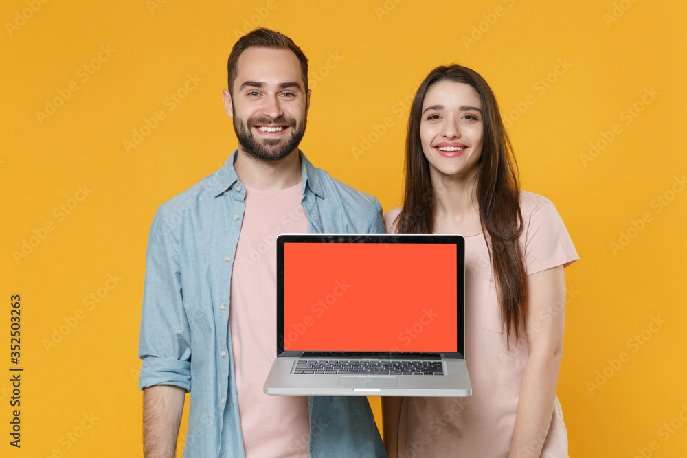 Smiling young couple friends guy girl in pastel blue casual clothes posing isolated on yellow background. People lifestyle concept. Mock up copy space. Hold laptop pc computer with blank empty screen. Smiling young couple friends guy girl in pastel blue casual clothes posing isolated on yellow background. People lifestyle concept. Mock up copy space. Hold laptop pc computer with blank empty screen.