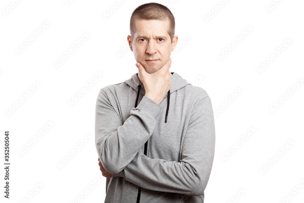 brooding, insecure male athlete makes a decision, a hand at the chin. Dressed in a grey hooded jacket. A look into the camera. Isolated brooding, insecure male athlete makes a decision, a hand at the chin. Dressed in a grey hooded jacket. A look into the camera. Isolated