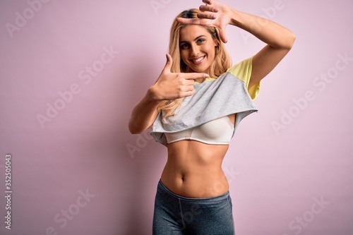 Young beautiful blonde sportswoman doing sport wearing sportswear over pink background smiling making frame with hands and fingers with happy face. Creativity and photography concept.