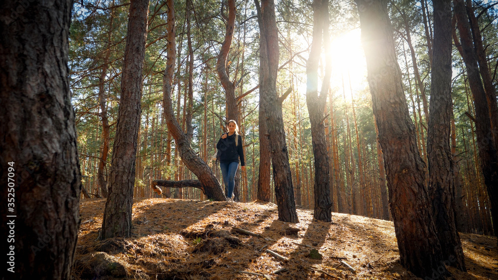 Beautiful young female hiker walking in forest at sunset