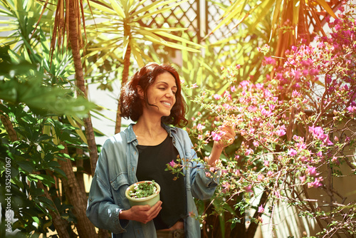 Woman on a terrace with a pot in her arms.