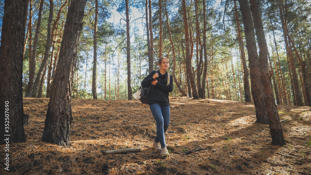 Toned photo of tired female tourist with heavy backpack walking on hiking route in forest Toned photo of tired female tourist with heavy backpack walking on hiking route in forest