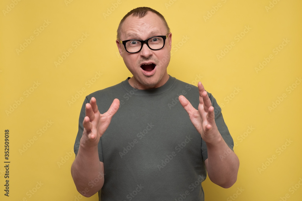 Portrait of mature caucasian man with shocked facial expression, isolated over yellow background Portrait of mature caucasian man with shocked facial expression, isolated over yellow background