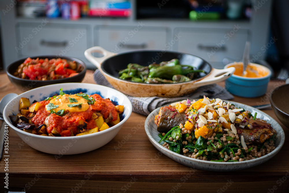 Patatas Bravas in a bowl, surrounded by Padron peppers and fish. Healthy Spanish food taken landscape Patatas Bravas in a bowl, surrounded by Padron peppers and fish. Healthy Spanish food taken landscape