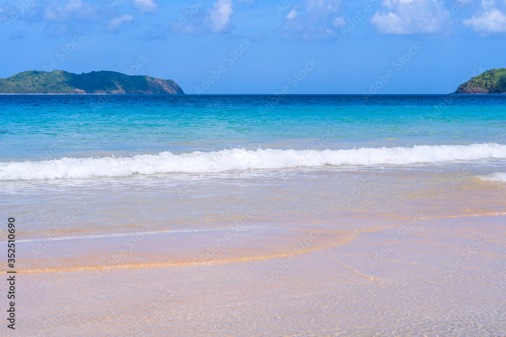 Obraz premium Beautiful amazing gold colored sandy beach with soft waves isolated with sunny blue sky. Concept of tropical calm tourism idea, copy space, close up