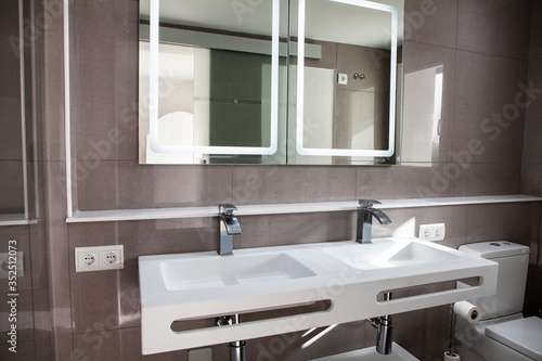 Spacious bathroom in gray tones with heated floors  walk-in shower  double sink vanity and skylights