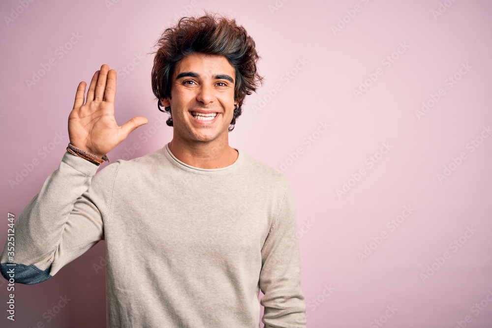 Young handsome man wearing casual t-shirt standing over isolated pink background Waiving saying hello happy and smiling, friendly welcome gesture Young handsome man wearing casual t-shirt standing over isolated pink background Waiving saying hello happy and smiling, friendly welcome gesture