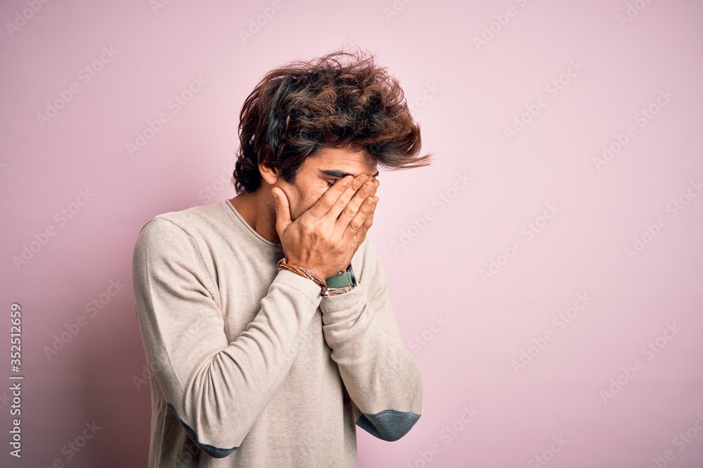 Young handsome man wearing casual t-shirt standing over isolated pink background with sad expression covering face with hands while crying. Depression concept. Young handsome man wearing casual t-shirt standing over isolated pink background with sad expression covering face with hands while crying. Depression concept.