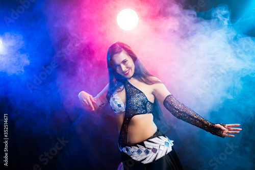 Young woman belly dancer in exotic dress with gold, dancing tribal fusion dance in studio. © satura_