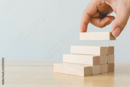 Hand arranging wood block stacking as step stair. Ladder career path concept for business growth success process photo