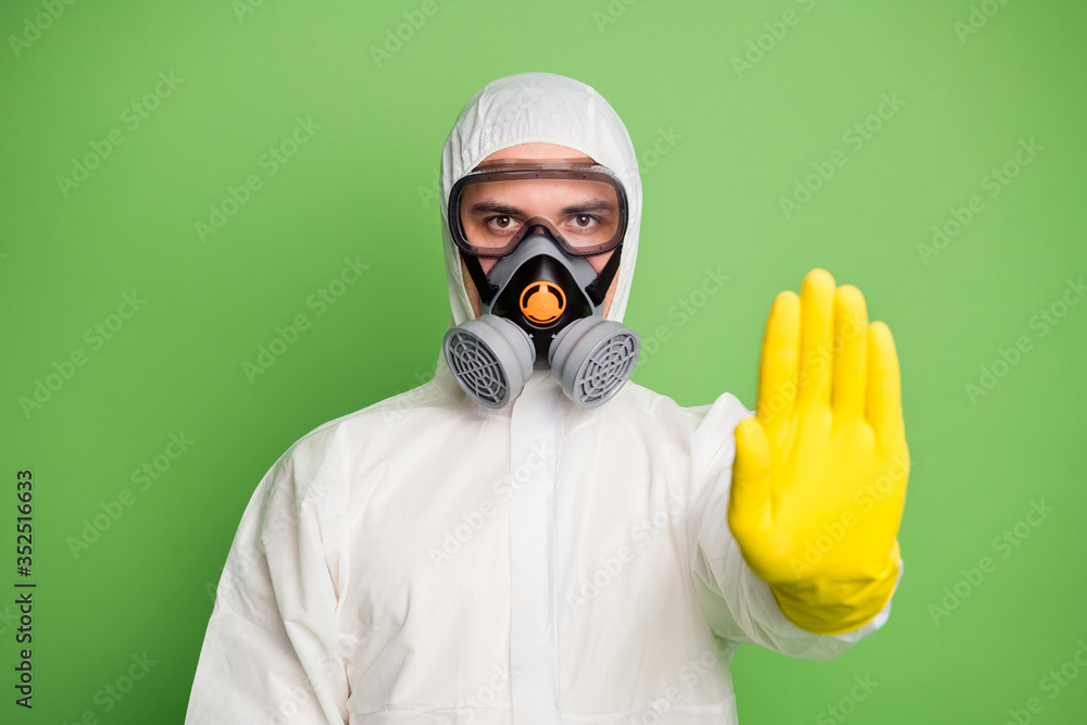 Close-up portrait of his he nice serious disinfectant workman wearing gas mask showing palm stop sign quarantine keep social distance isolated over green pastel color background Close-up portrait of his he nice serious disinfectant workman wearing gas mask showing palm stop sign quarantine keep social distance isolated over green pastel color background