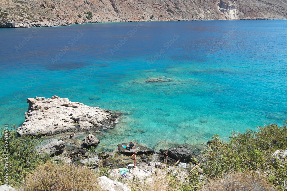 Clear blue waters at the coast on the south of Crete, Greece, at Loutro village.  A rocky waters edge. Unspoiled Greek countryside on a summers day with a view of the crystal clear Aegean sea.