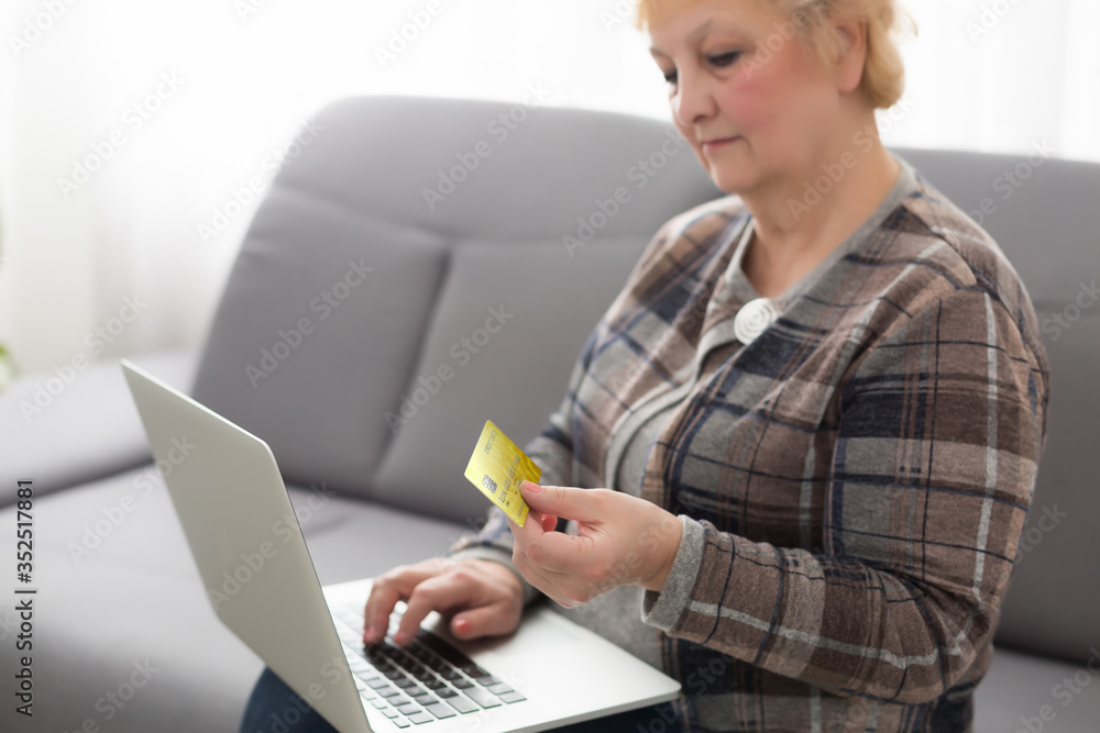 Smiling senior woman using credit card and laptop Smiling senior woman using credit card and laptop