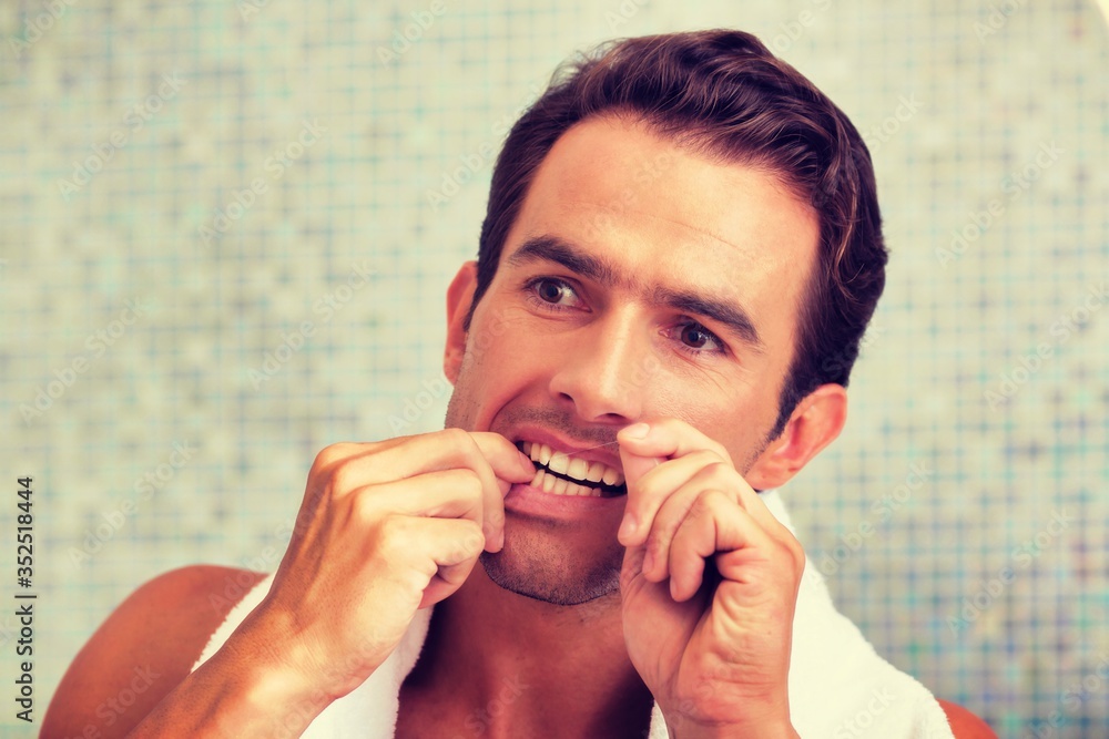Portrait of Attractive man flossing in bathroom
Portrait of Attractive man flossing in bathroom