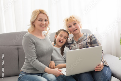 Grandmother and daughter teaching child use laptop application, playing game © Angelov