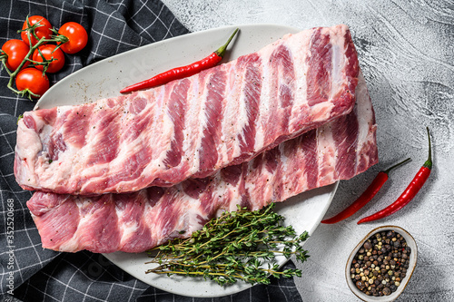 Fresh raw lamb spare ribs with spices and herbs. Gray background. Top view