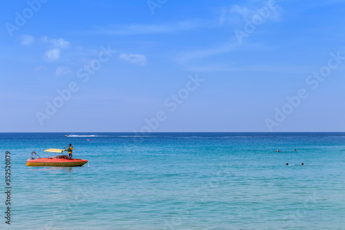 Life guard on the boat checking tourist swimming in the sea, summer outdoor day light, beautiful blue sea and clear blue sky, vacation destination to Asia