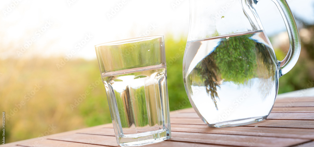 Φωτογραφία jug with water and a glass on a wooden table on the nature in the garden