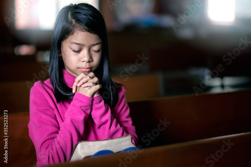 Girl sitting in church and praying for family members, Christian concept.