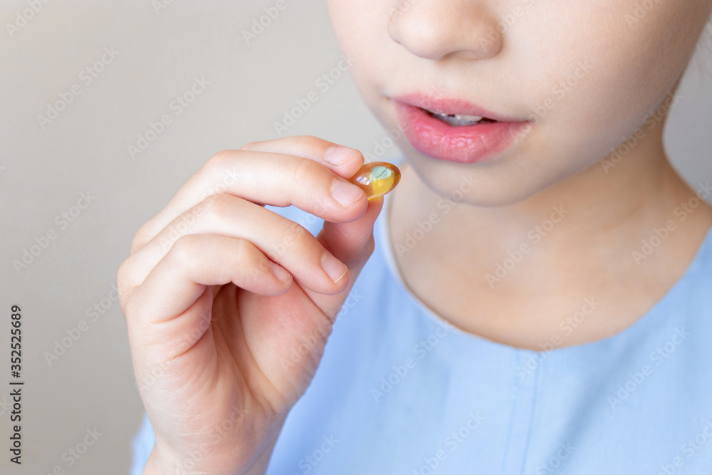 Close up child putting in mouth capsule omega 3 vitamin, fish oil Close up child putting in mouth capsule omega 3 vitamin, fish oil