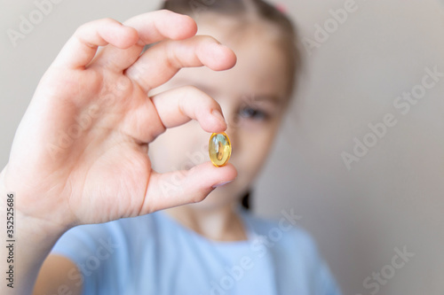 Foto Close up child holding in hand with omega 3 vitamin, fish oil