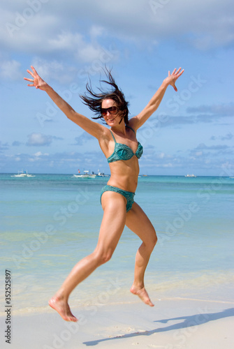 Frau im Bikini springt am Strand