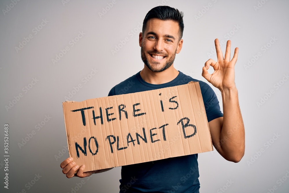 Young handsome activist man protesting for the enviroment hoding cardboard doing ok sign with fingers, excellent symbol Young handsome activist man protesting for the enviroment hoding cardboard doing ok sign with fingers, excellent symbol