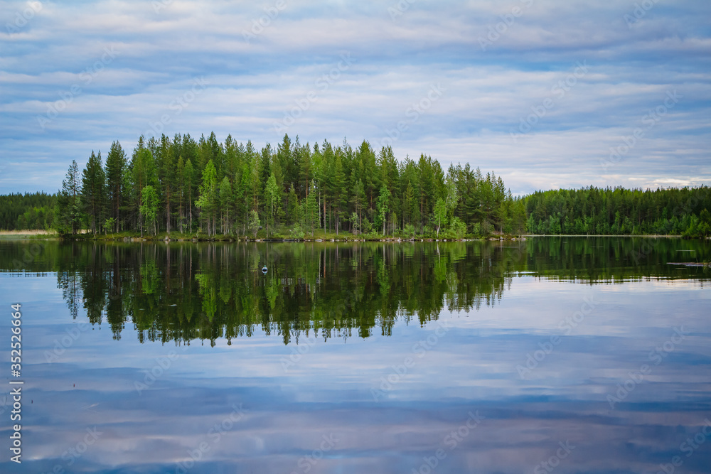 Karelian lakes at sunset and sunrise. Clouds and trees are reflected in the lake