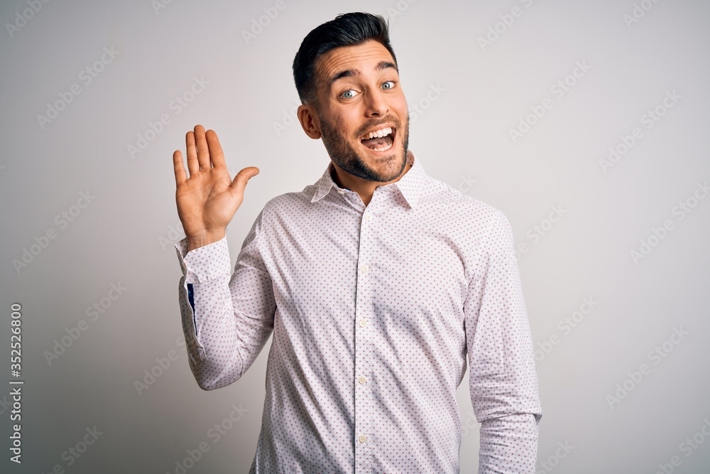 Young handsome man wearing elegant shirt standing over isolated white background Waiving saying hello happy and smiling, friendly welcome gesture Young handsome man wearing elegant shirt standing over isolated white background Waiving saying hello happy and smiling, friendly welcome gesture
