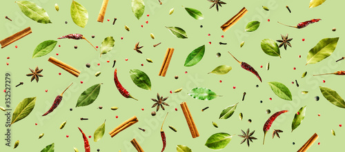 Flying spices Bay leaf, red chili pepper, anise, cinnamon sticks on a green background. Long food pattern banner.