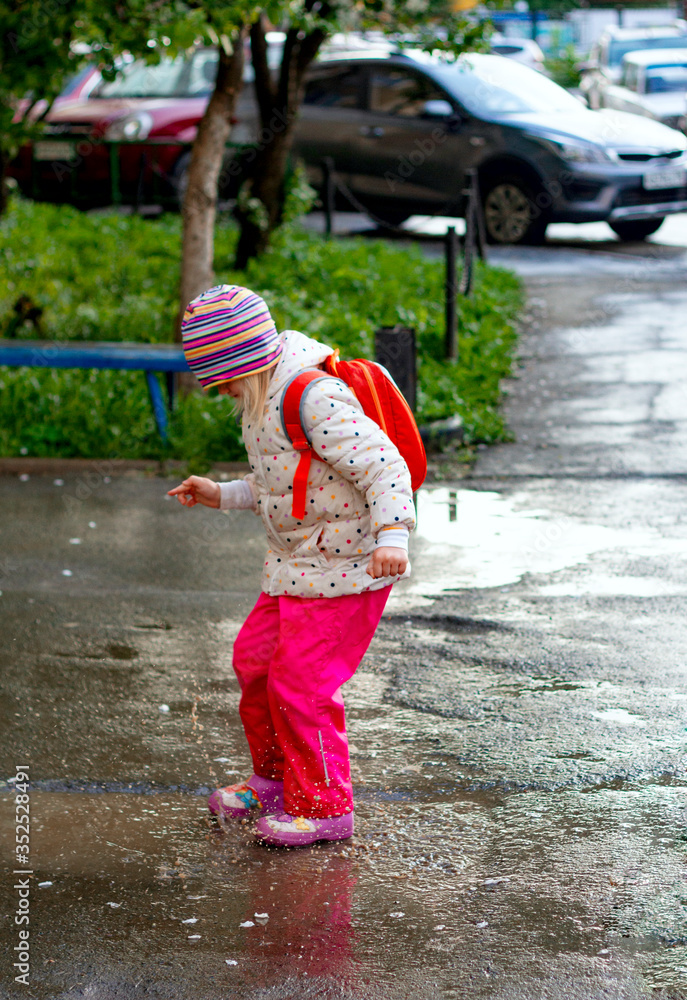 Pretty toddler girl wearing colorful raincoats and rain boots jumping in muddy puddles. Pretty toddler girl wearing colorful raincoats and rain boots jumping in muddy puddles.