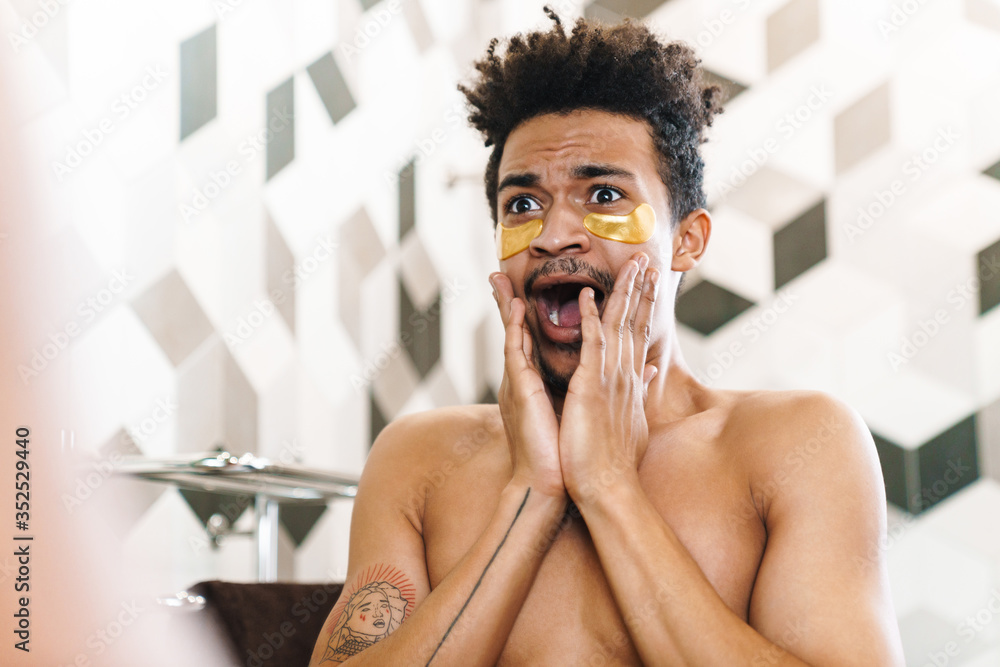 Photo of african american man with eye patches looking at mirror Photo of african american man with eye patches looking at mirror